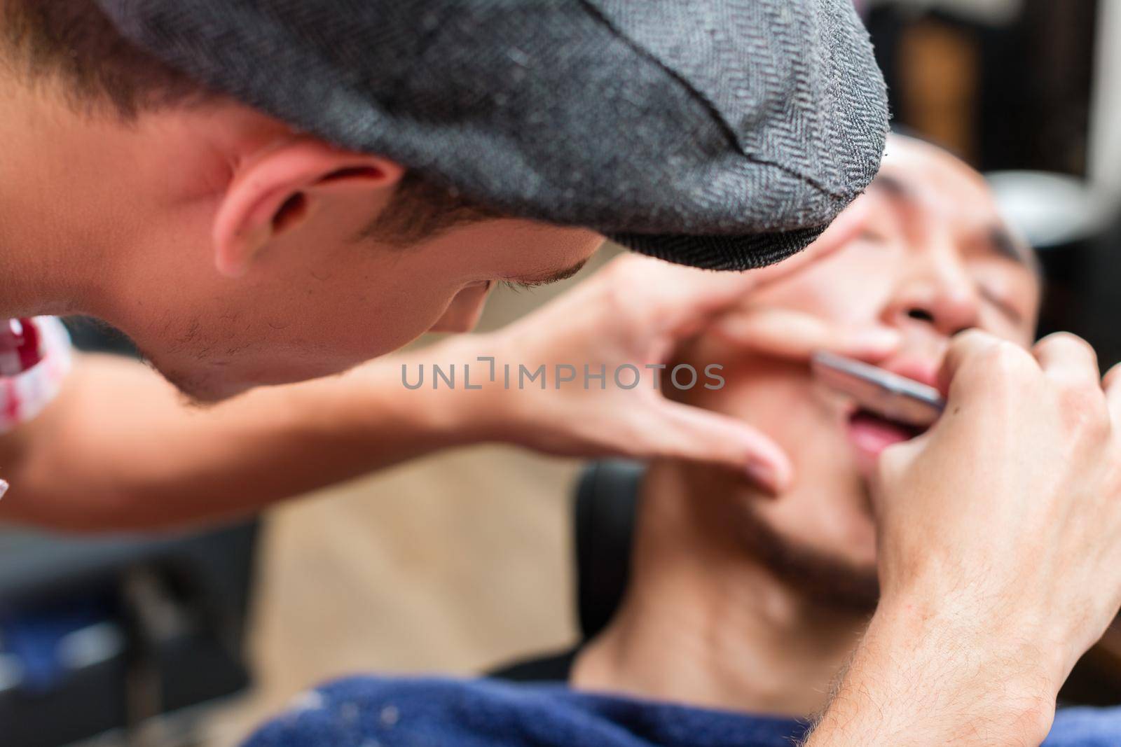 Close-up of male hairdresser shaving man's moustache in salon