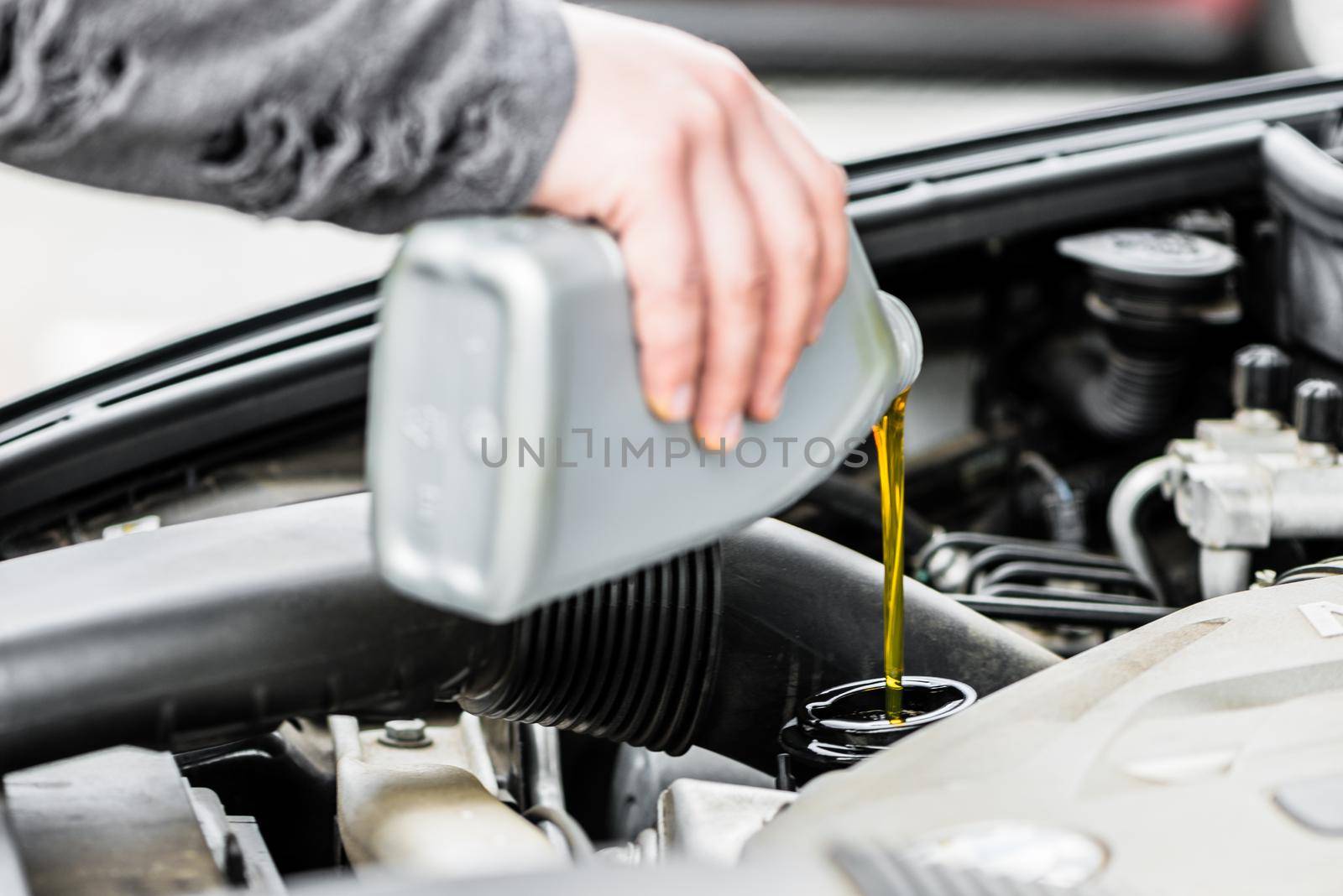 Woman putting oil into the engine of her car by Kzenon