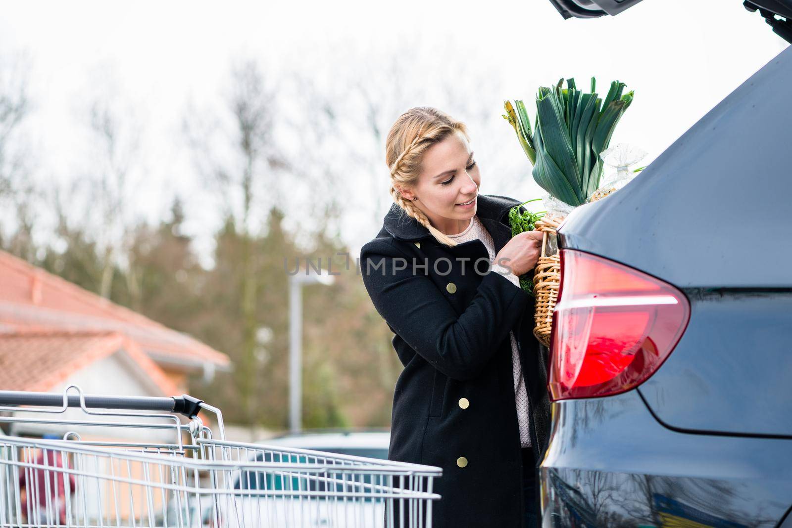Woman loading groceries after shopping into trunk of her car by Kzenon