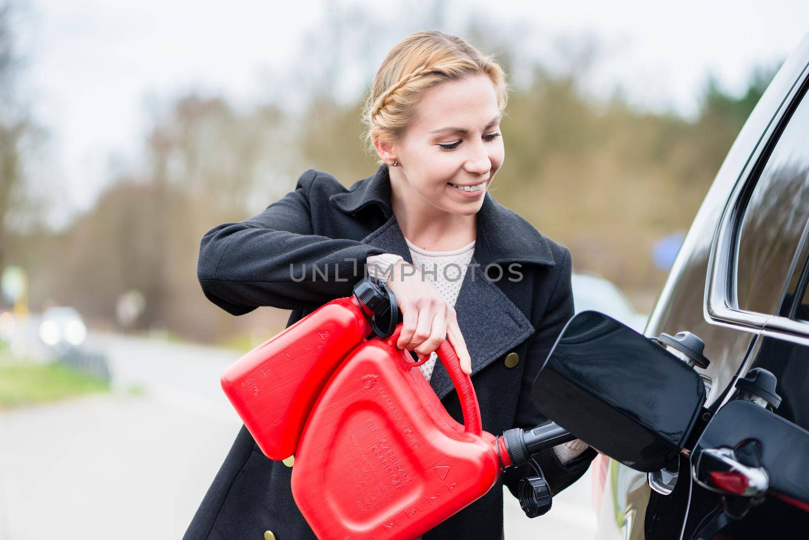 Woman filling car up with gas from the spare canister by Kzenon