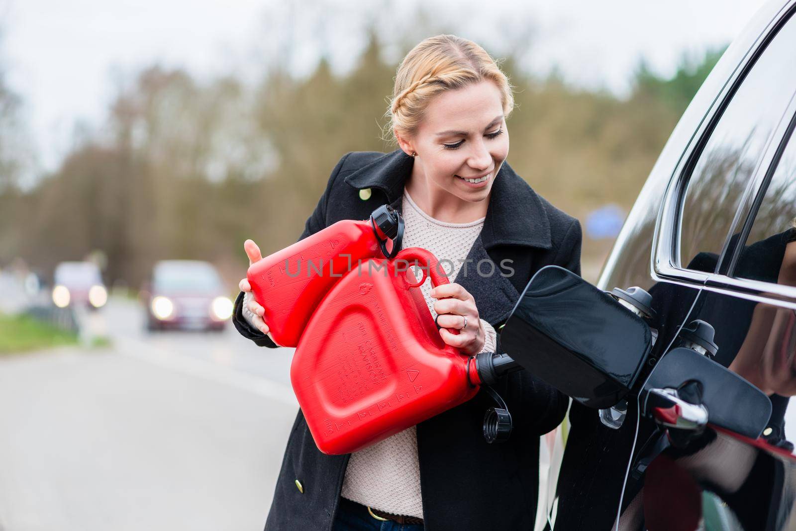 Woman filling car up with gas from the reserve canister happy she has one