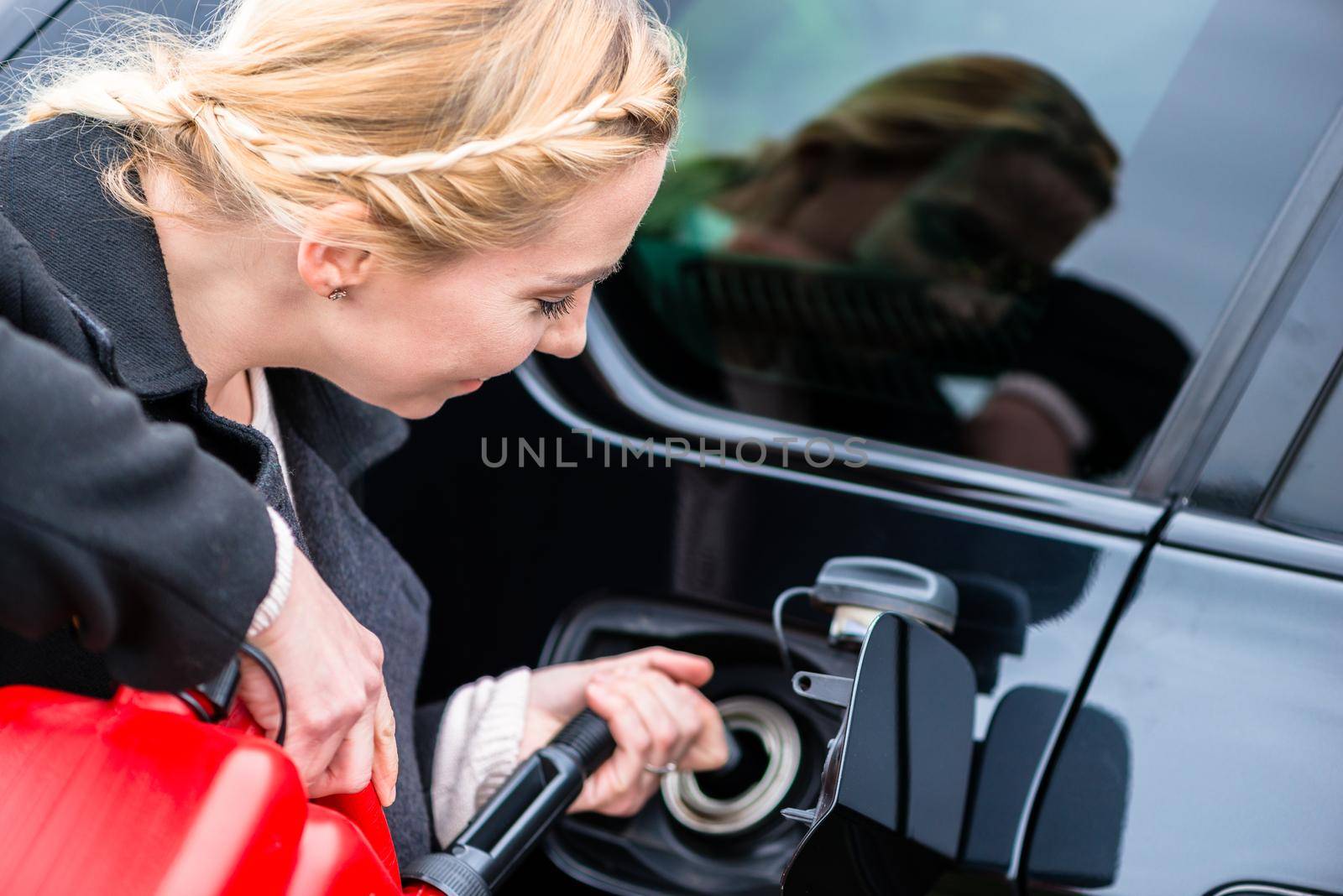 Woman filling car up with gas from the reserve canister happy she has one