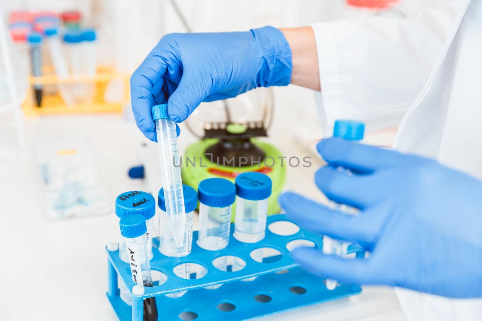 Closeup of young female scientist wearing blue gloves holding test tube researching in clinical laboratory