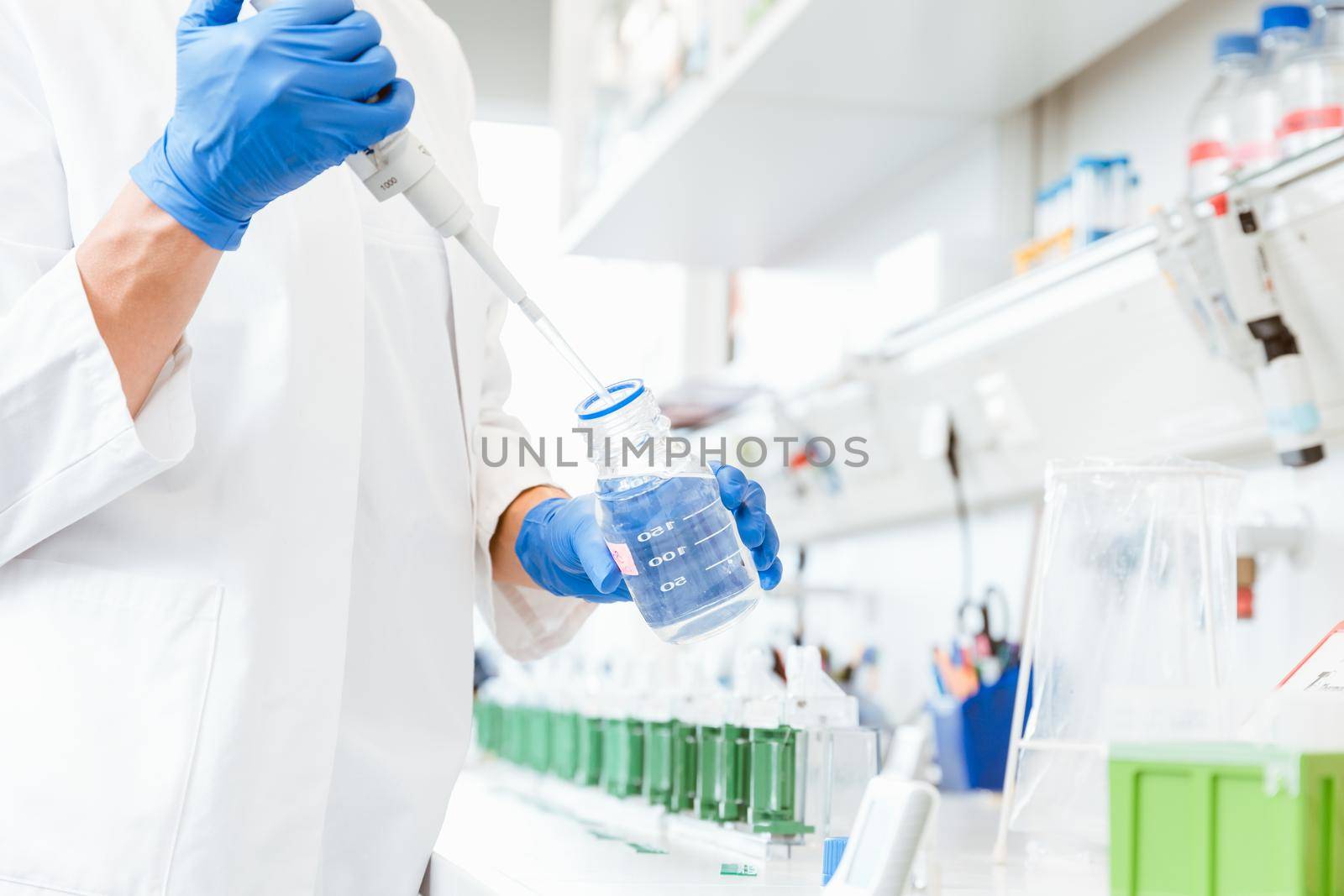 Closeup of a doctors hand wearing blue gloves using a dropper to suspense sample from bottle