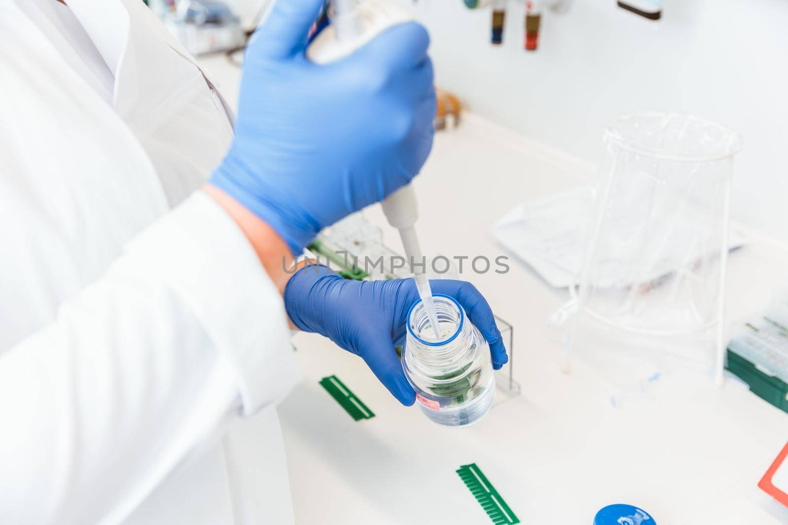 Closeup of a doctor hands using dropper to remove liquid from bottle for experiment