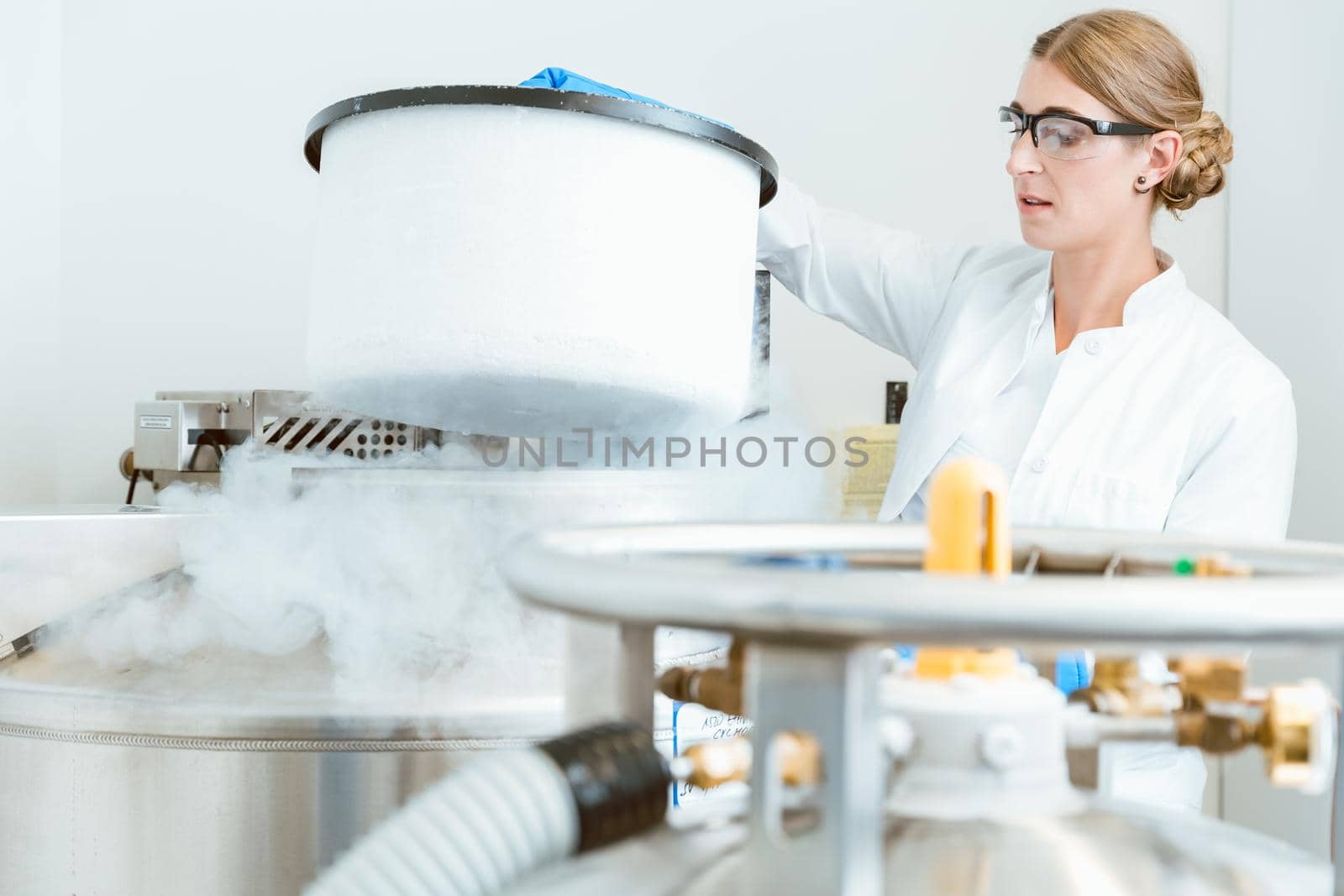 Side view of young female caucasian scientist wearing glasses lifting lid of machine in laboratory