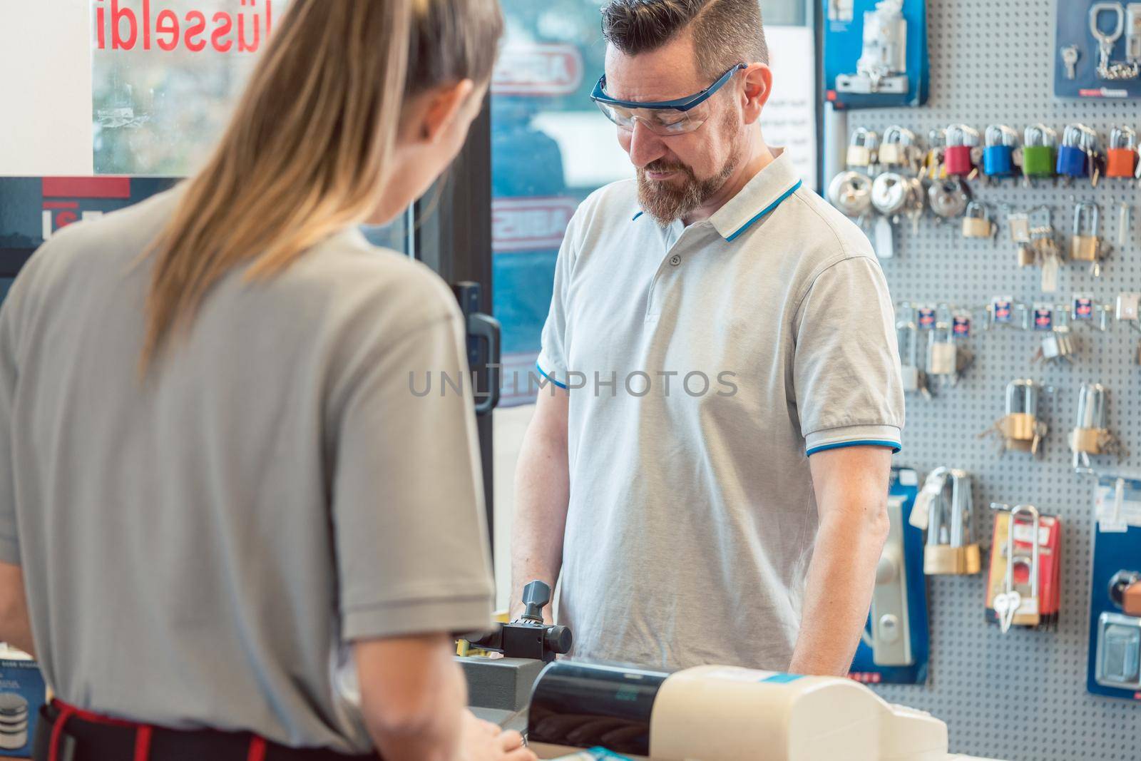 Woman customer talking to keymaker or locksmith in his shop