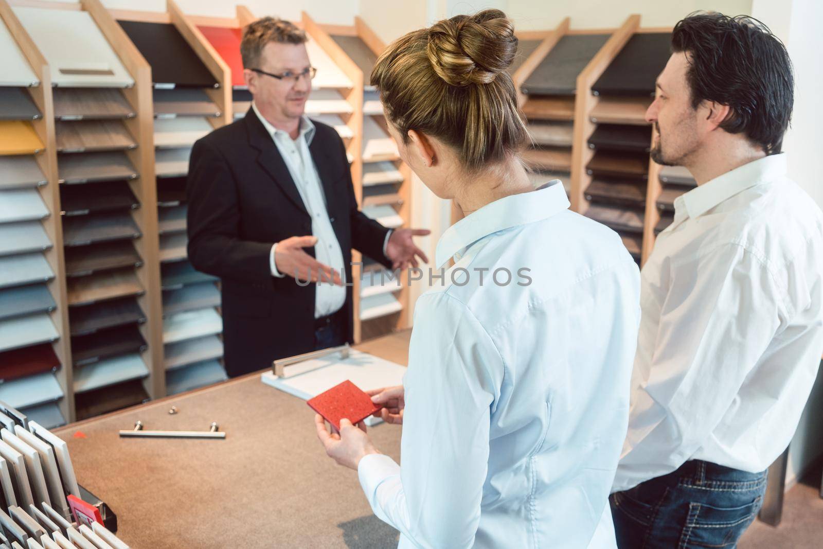 Woman, man, and expert discussing details of new kitchen finish with sales expert