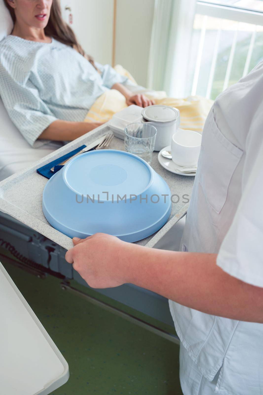 Nurse serving food in the hospital to a patient in bed, top view