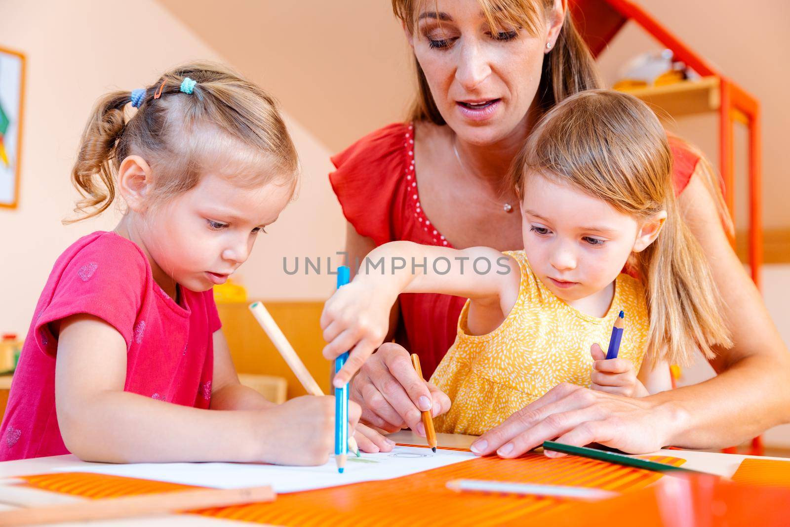 Children and play school teacher drawing together with pencils