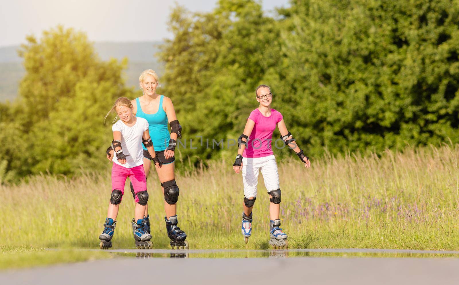 Mother and daughters rollerblading with in-line skates on country lane