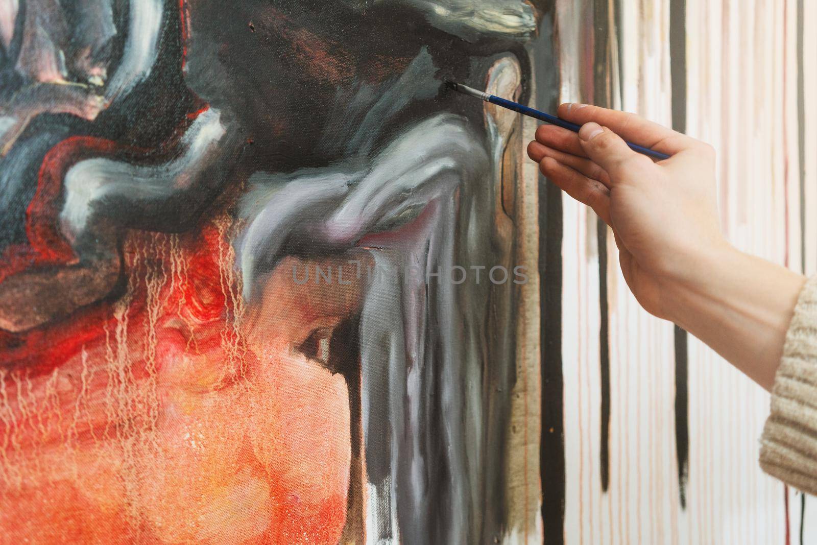 Hand of professional artist holding paint brush and making abstract painting in art studio