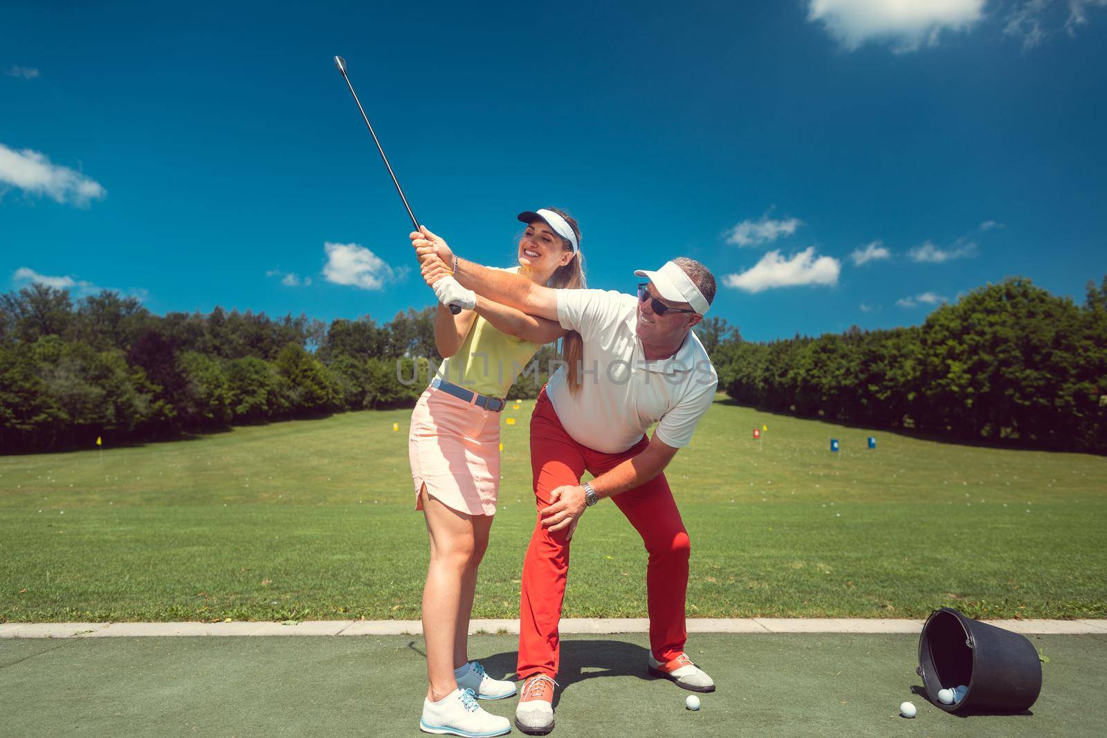 Golf pro teaching a woman student of the driving range by Kzenon