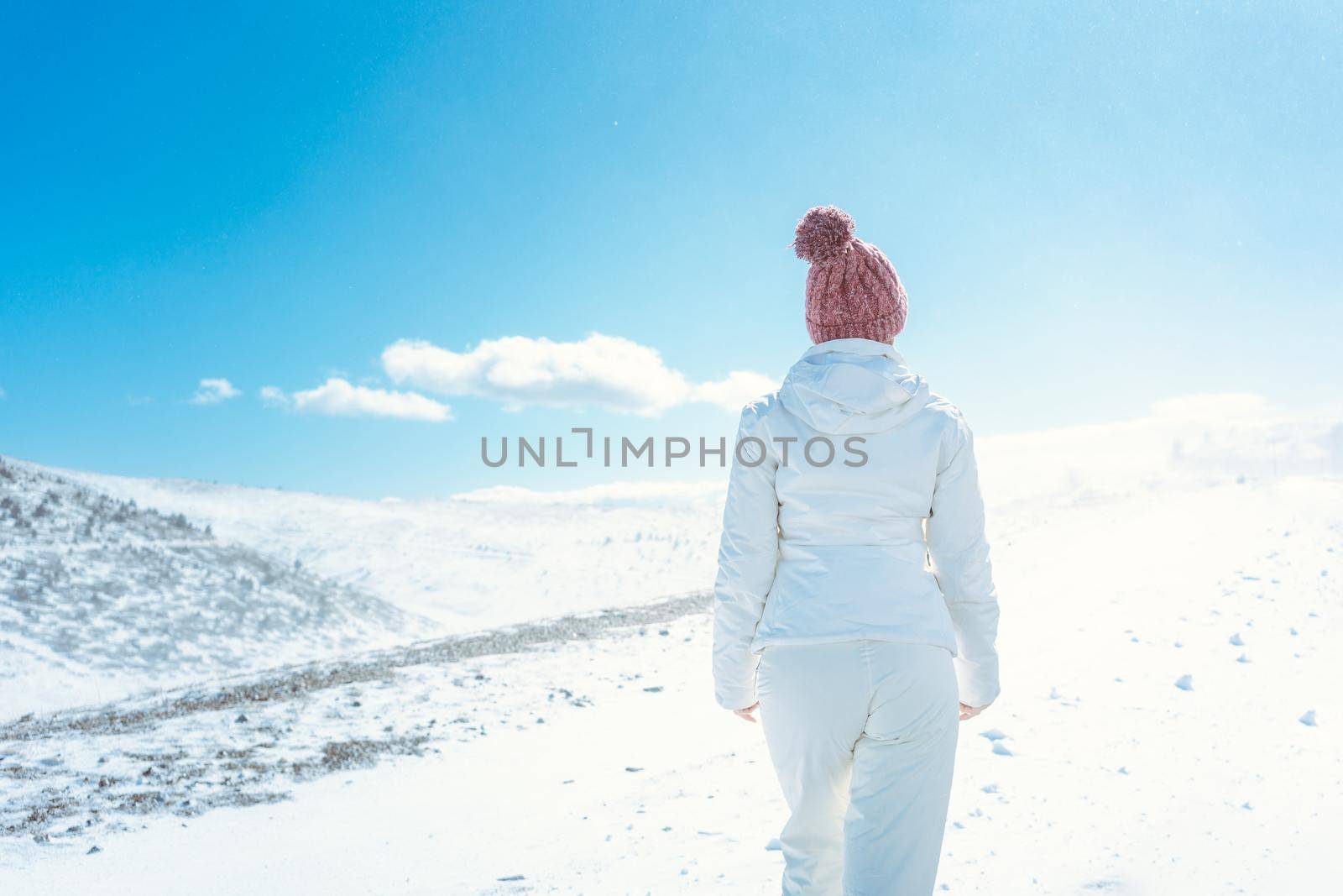 Woman looking at the first snow in the mountains seen from behind