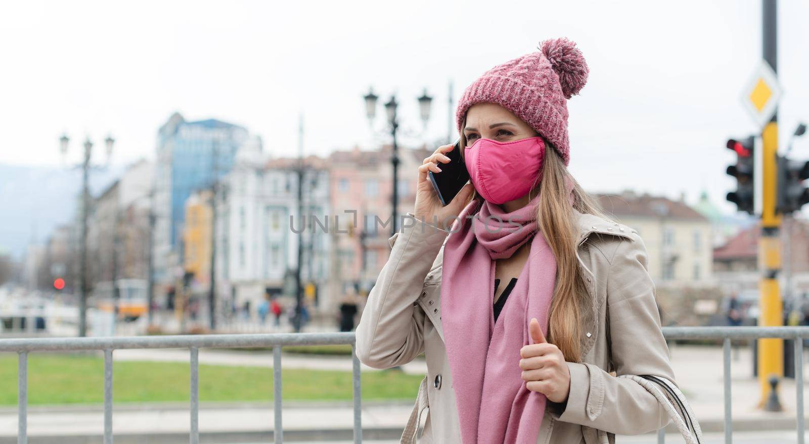 Woman with fashion mask using her phone by Kzenon