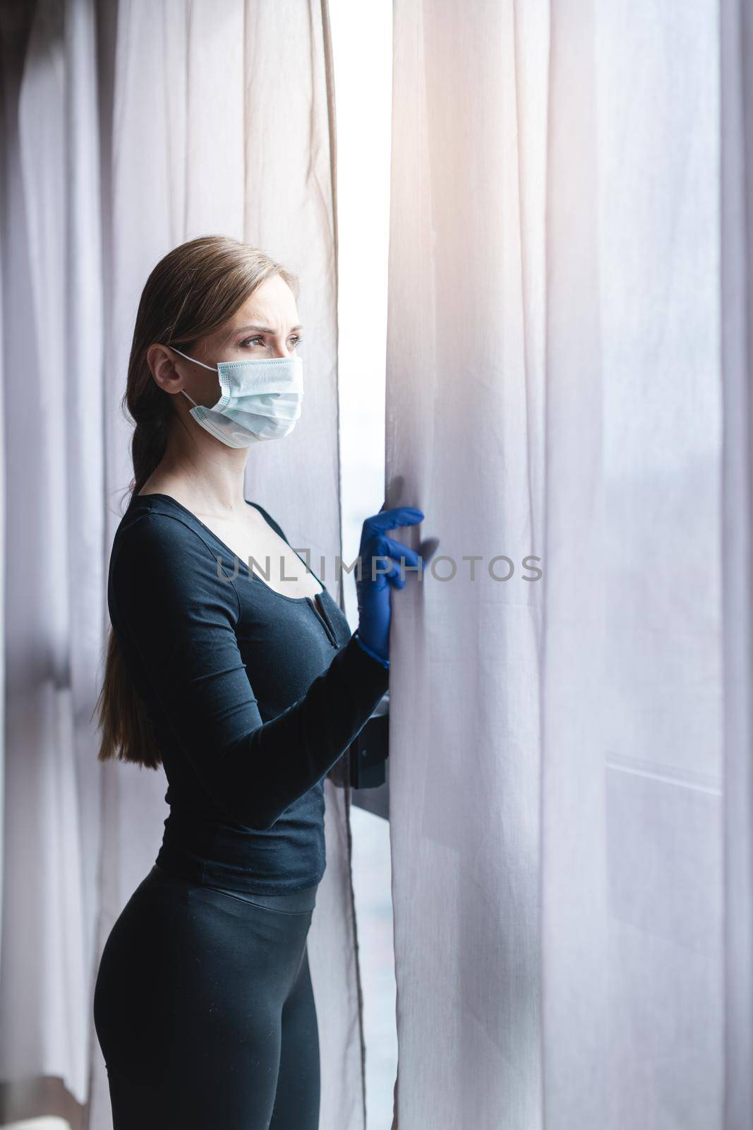 Bored woman in corona quarantine or under curfew looking out of window to the street