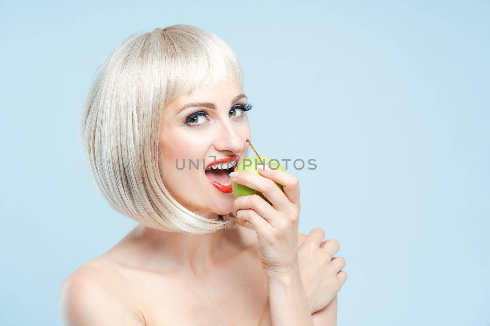 Beautiful woman eating green apple for weight loss smiling at the camera