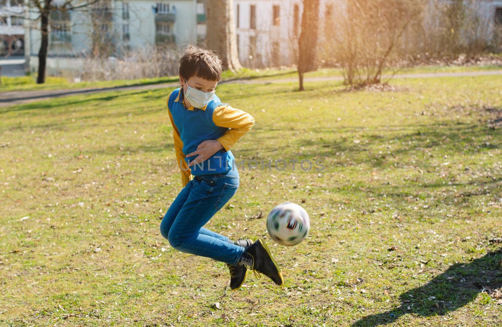 Boy playing football in the park despite the Covid-19 crisis by Kzenon