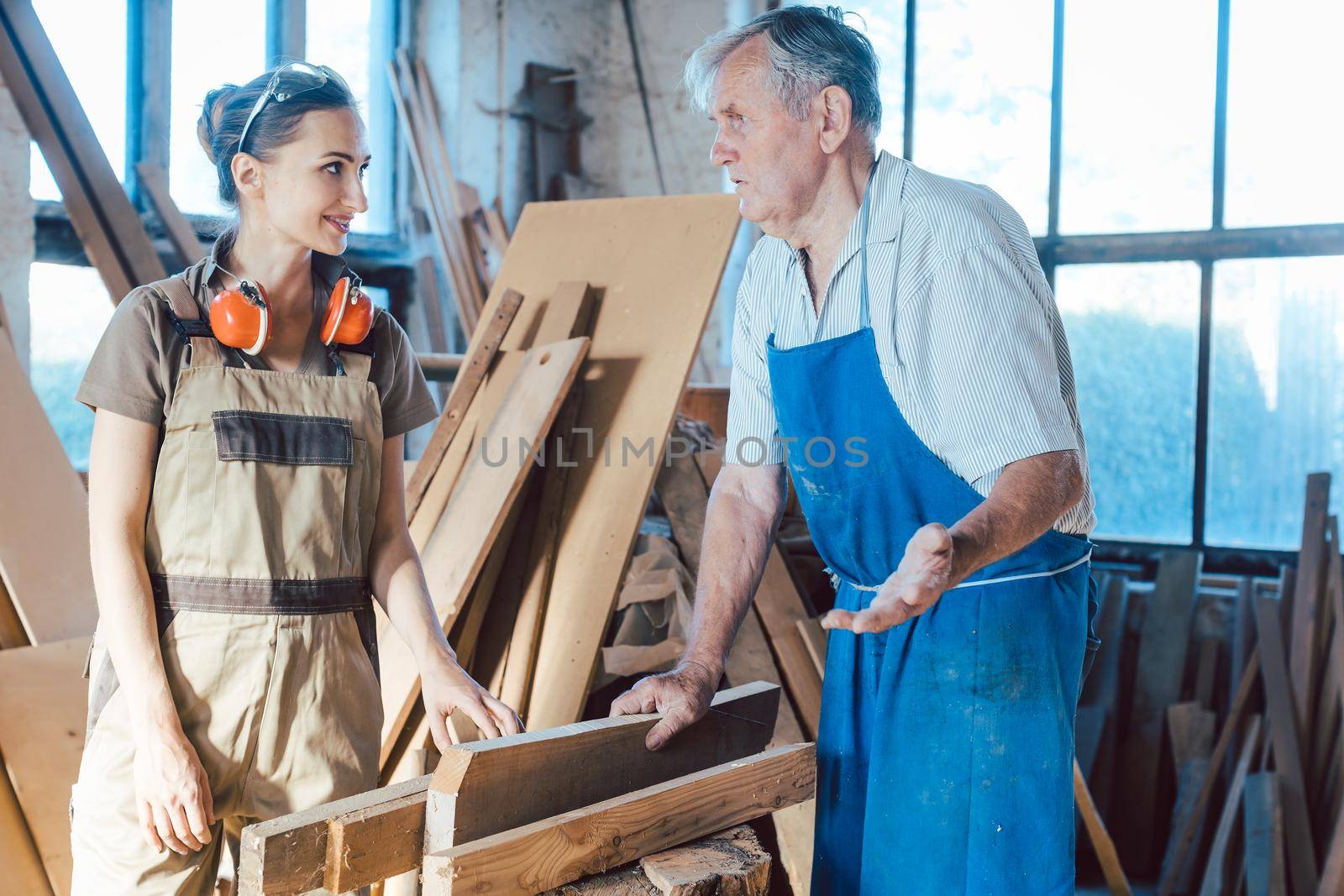 Senior carpenter sharing wisdom with younger aspiring colleague by Kzenon