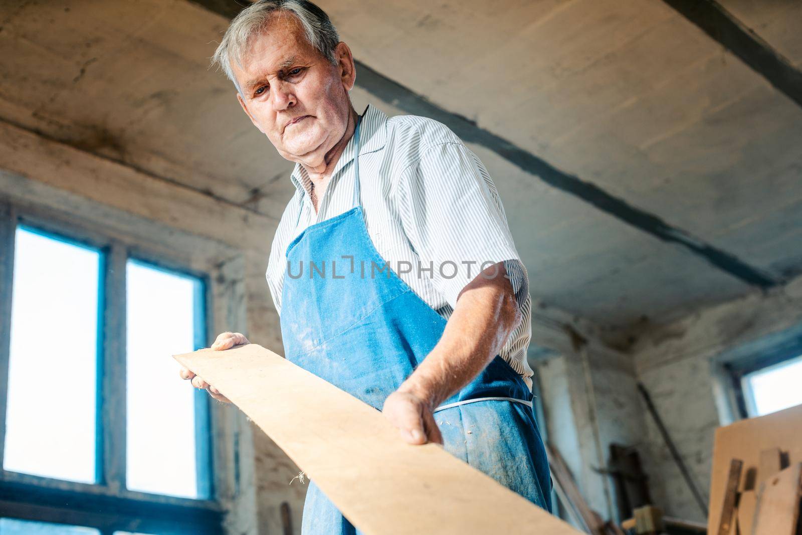 Experienced carpenter checking if a plank is plane and can be used