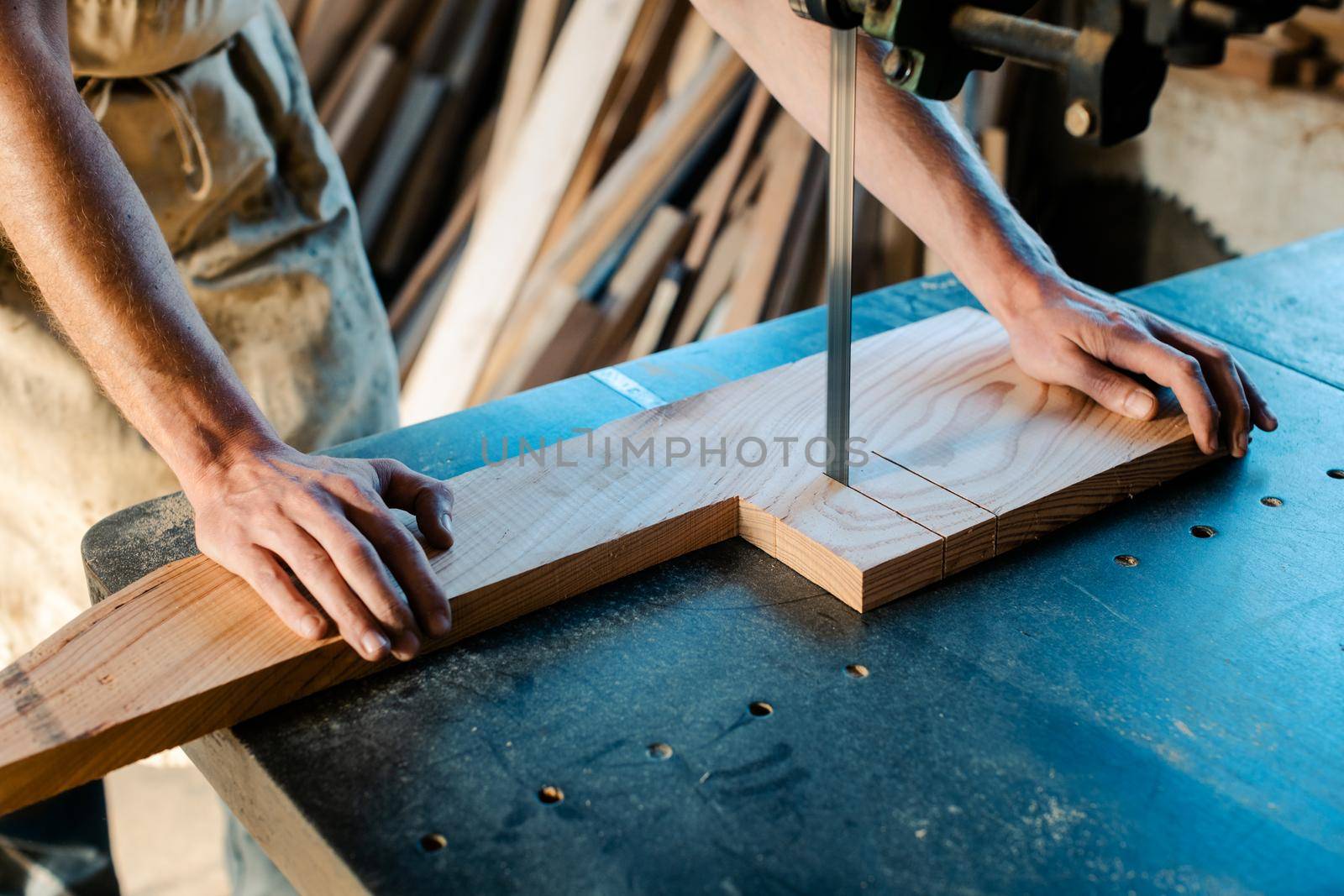 Close-up on carpenter using band saw to cut out piece of wood