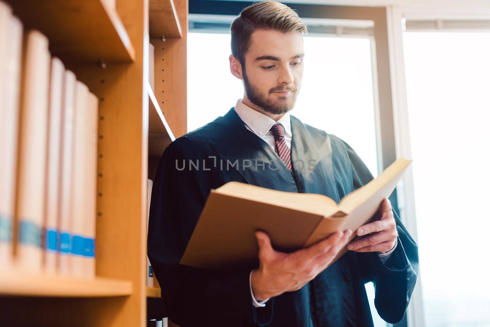 Lawyer with robe ready for court reading after the law one last time in the library of the firm