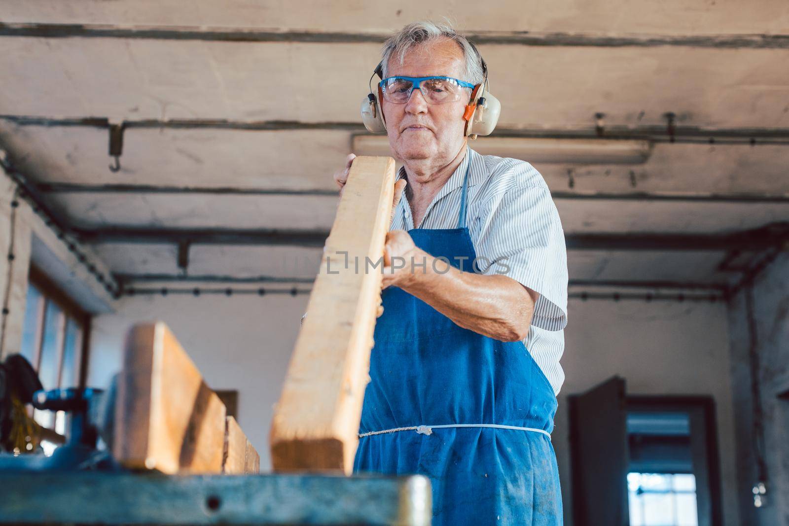 Experienced carpenter checking if a plank is plane and can be used