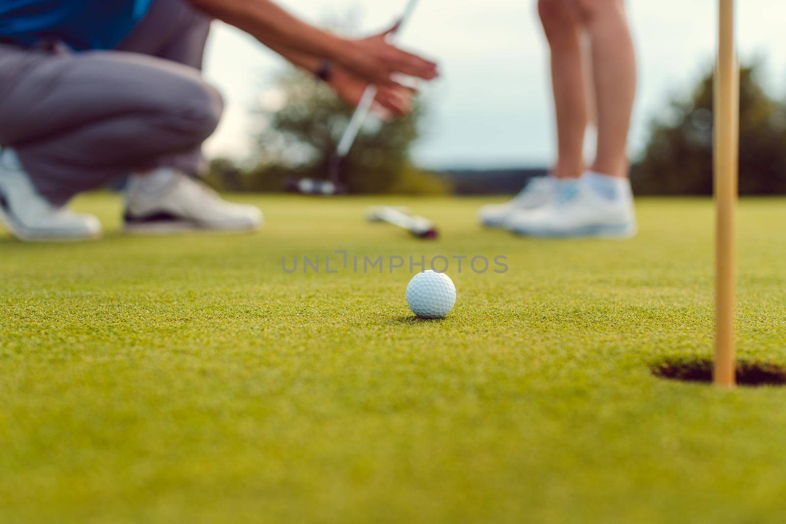 Pro on golf course teaching a woman how to put, close-up