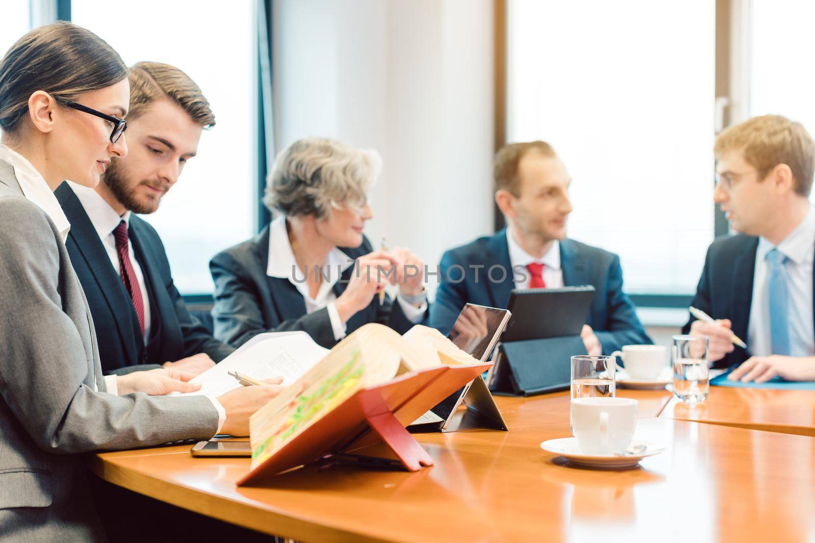 lawyer teams negotiating an agreement, computers, books and documents on the desk