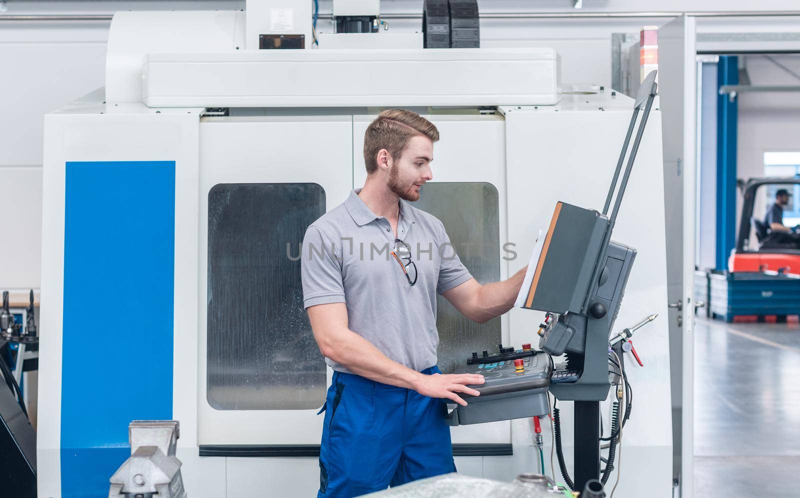 Worker operating computer-controlled machine tool on the screen