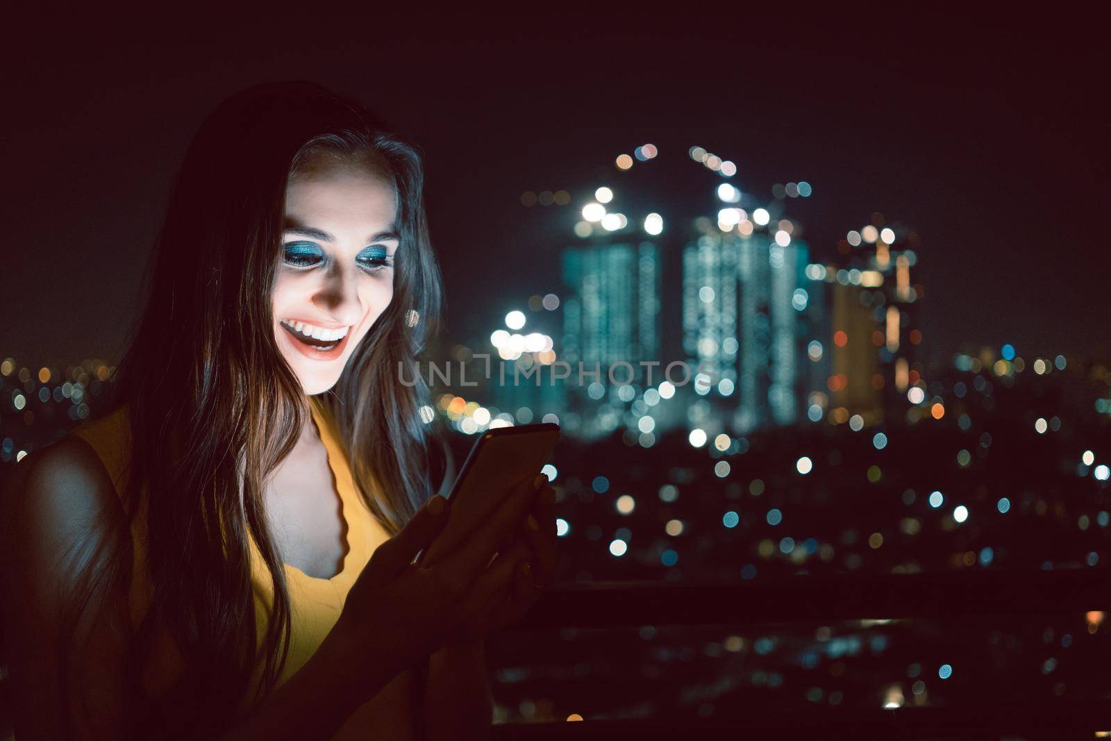 Woman checking her phone in front of big city skyline