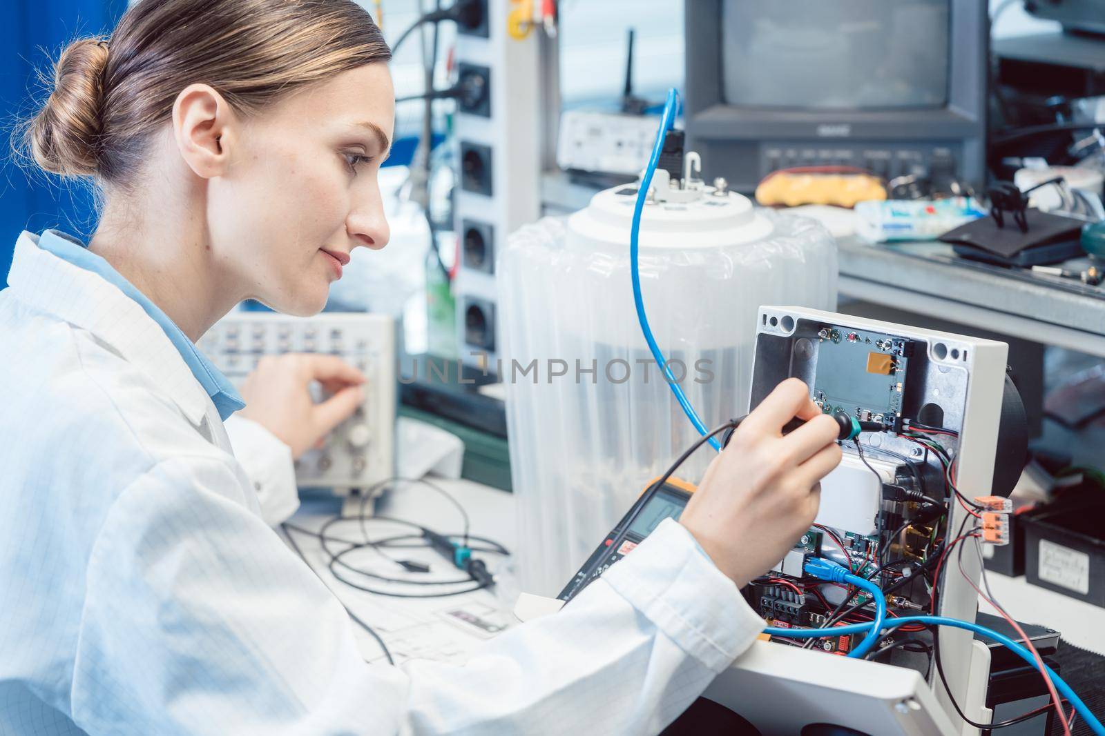 Engineer woman measuring electronic product on test bench in her lab for EMC compliance