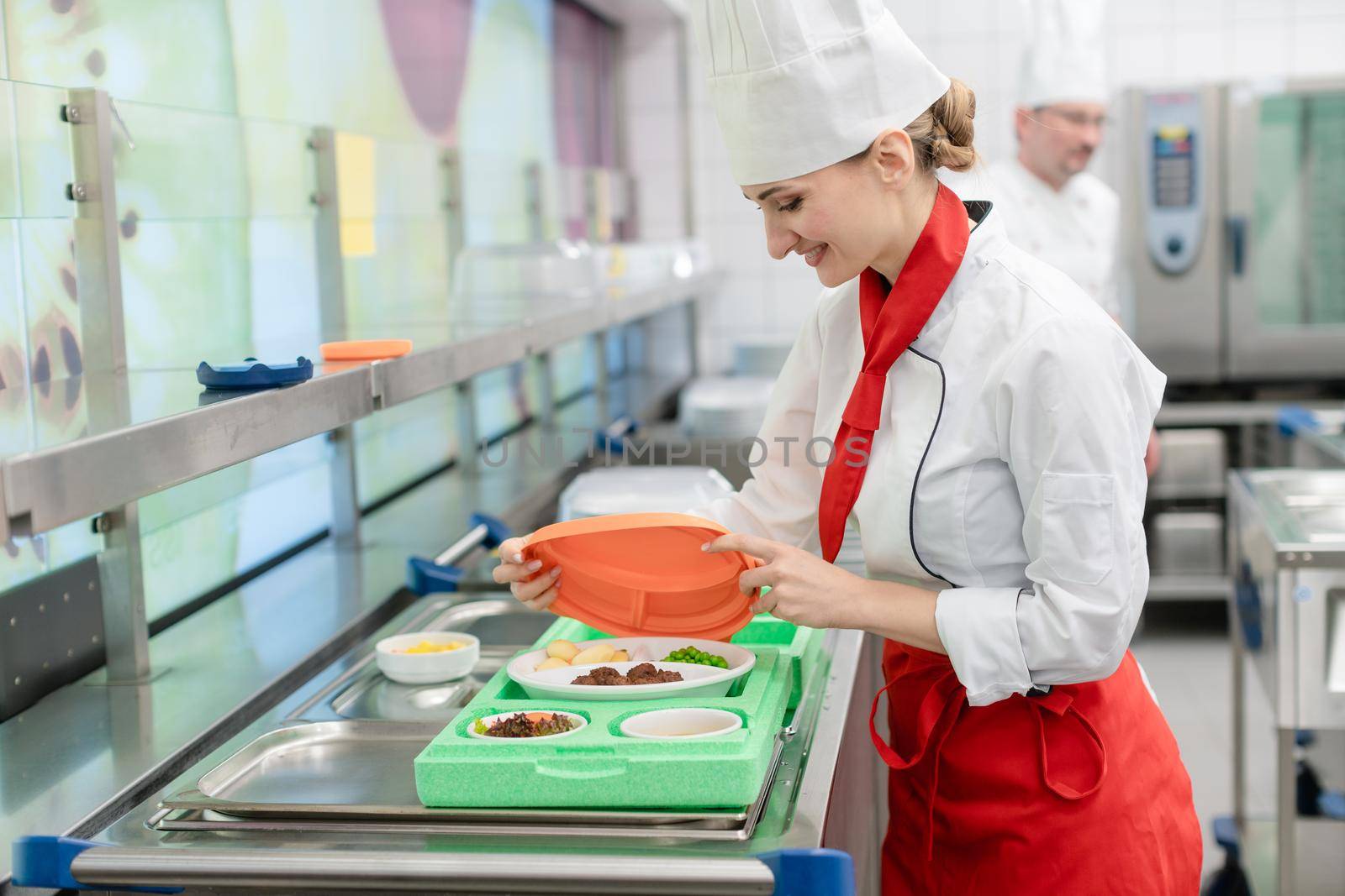 Chef in commercial kitchen preparing meal for delivery by Kzenon