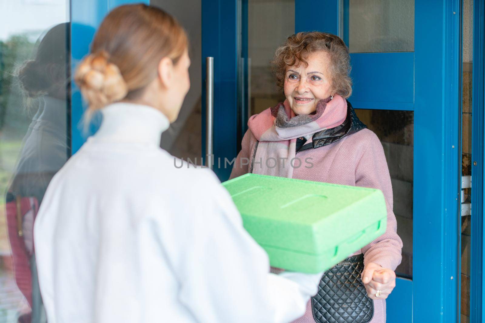 Volunteer delivering a hot meal to door of senior citizen