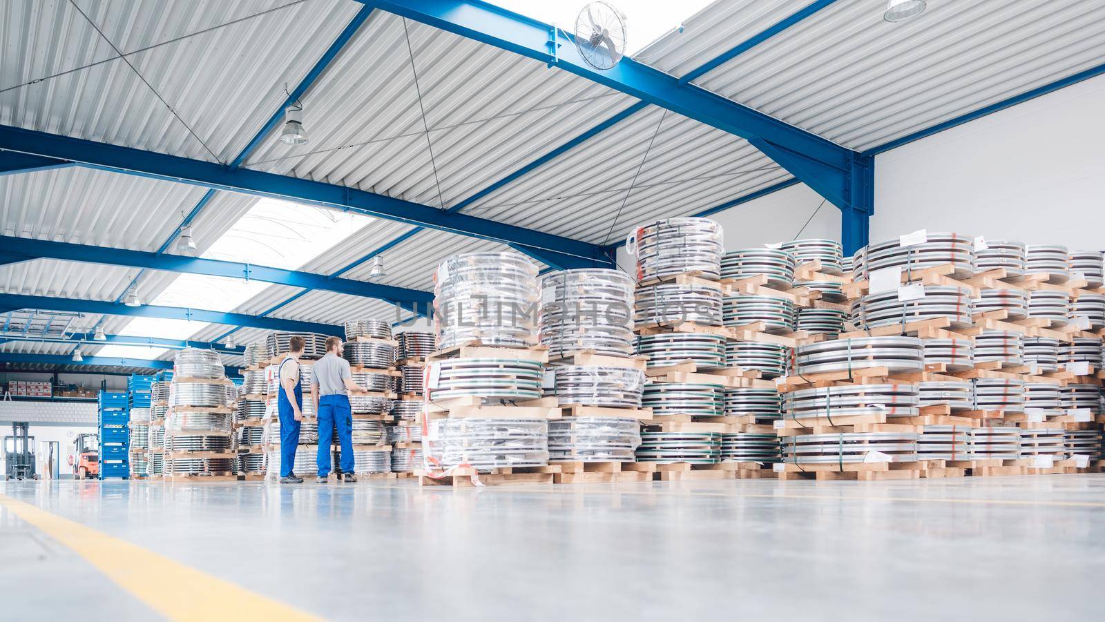 Workers looking at industrial materials in inventory of warehouse needing to be shipped