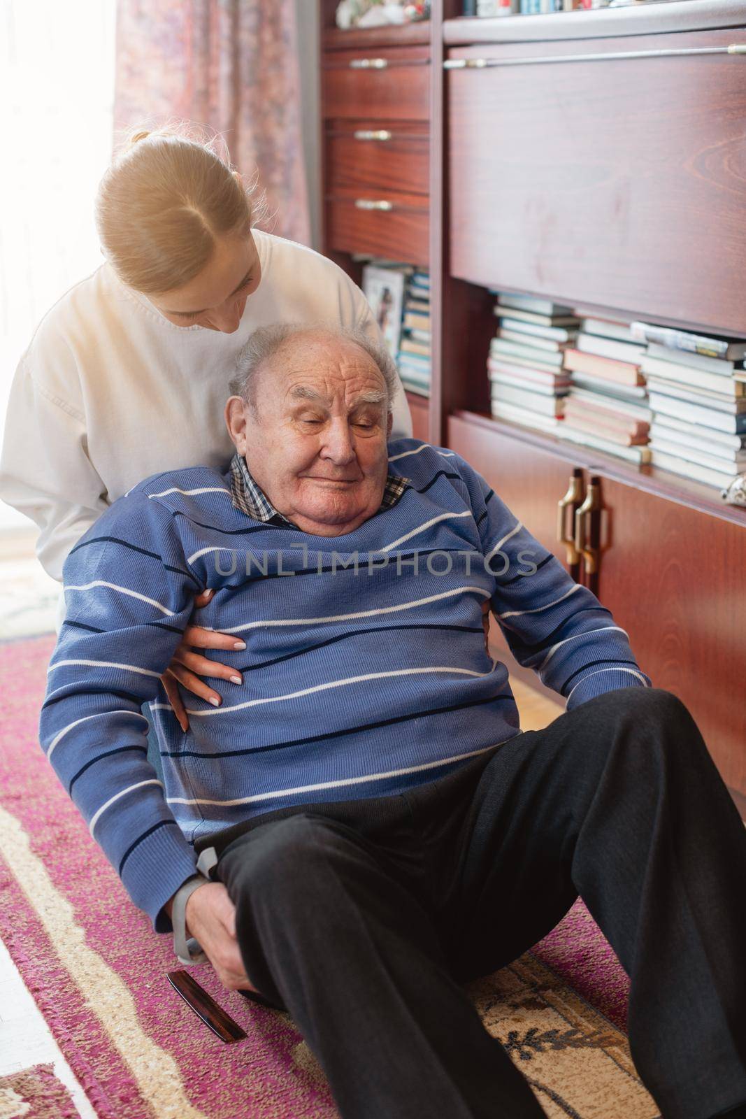 Nurse helping senior man getting up after he fell on the floor