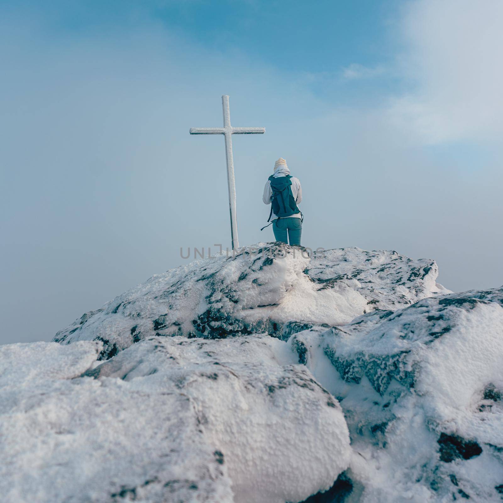 Woman standing near summit cross on a mountain summit