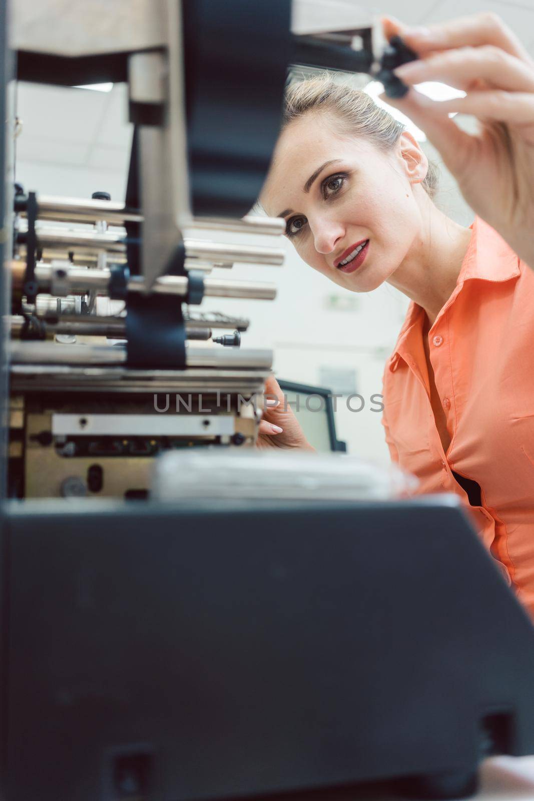 Diligent worker woman putting new labels in printing machine