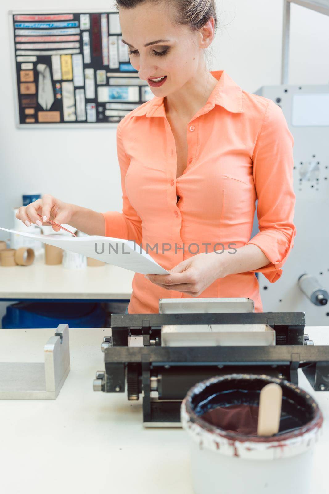 Worker checking design or a print to be run on printing machine by Kzenon