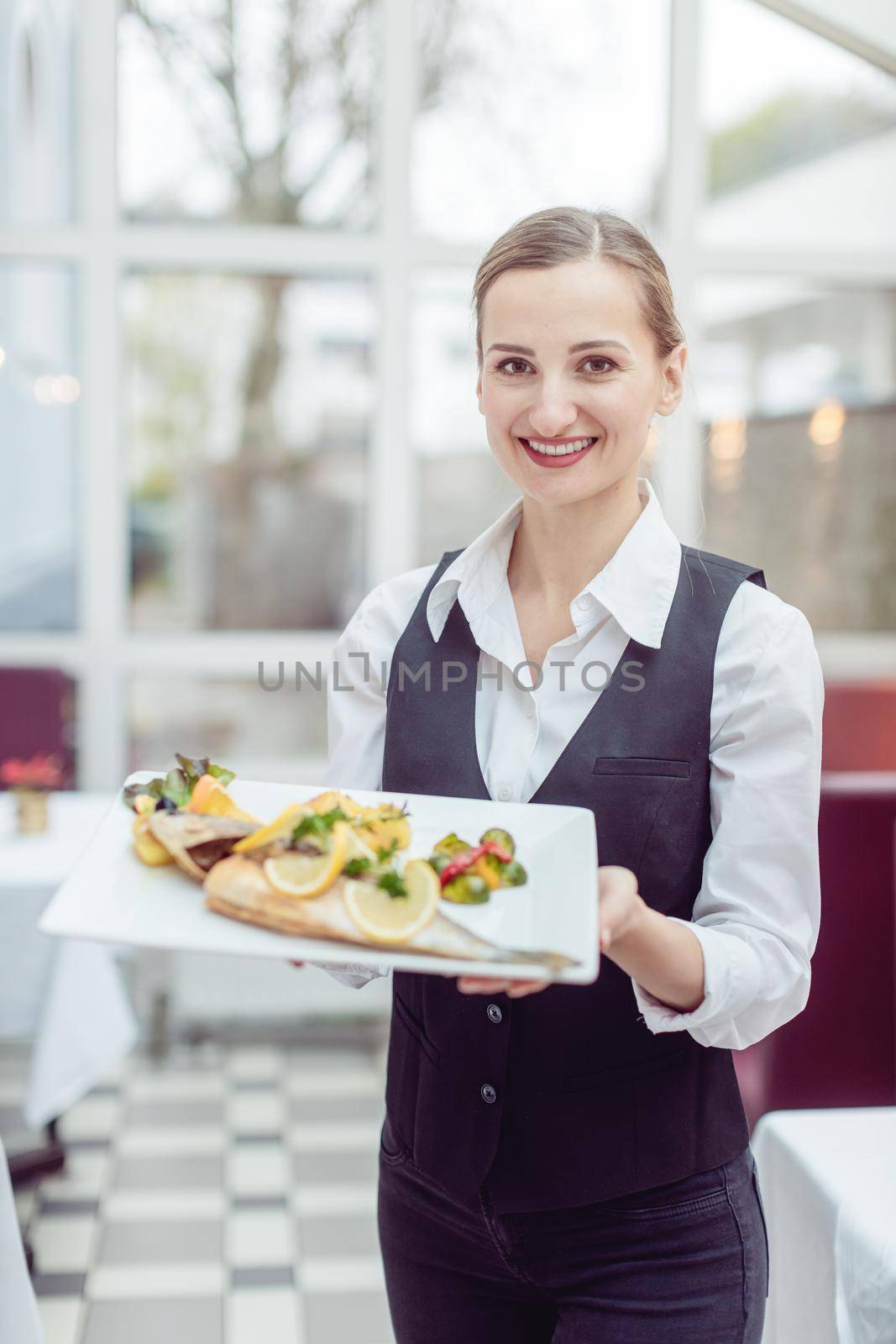 Waitress in a nice restaurant presenting a tasty dish by Kzenon