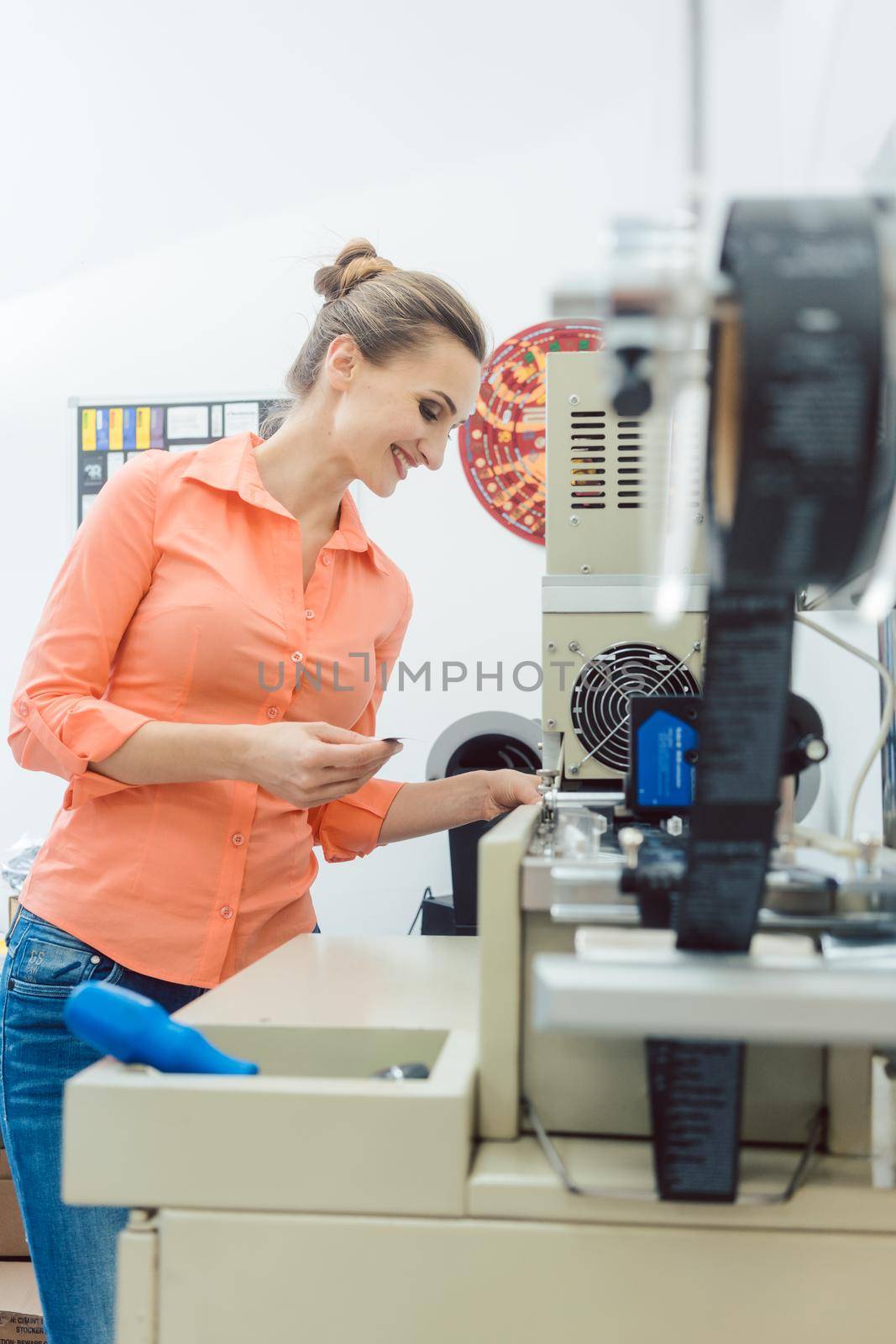 Worker checking textile label fresh from the printing machine by Kzenon