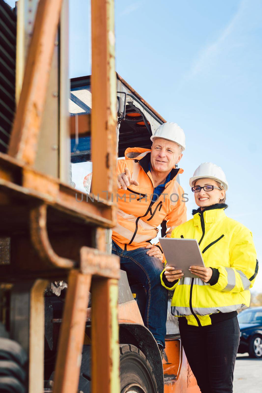 Supervisor woman instructing forklift driver what to work on next