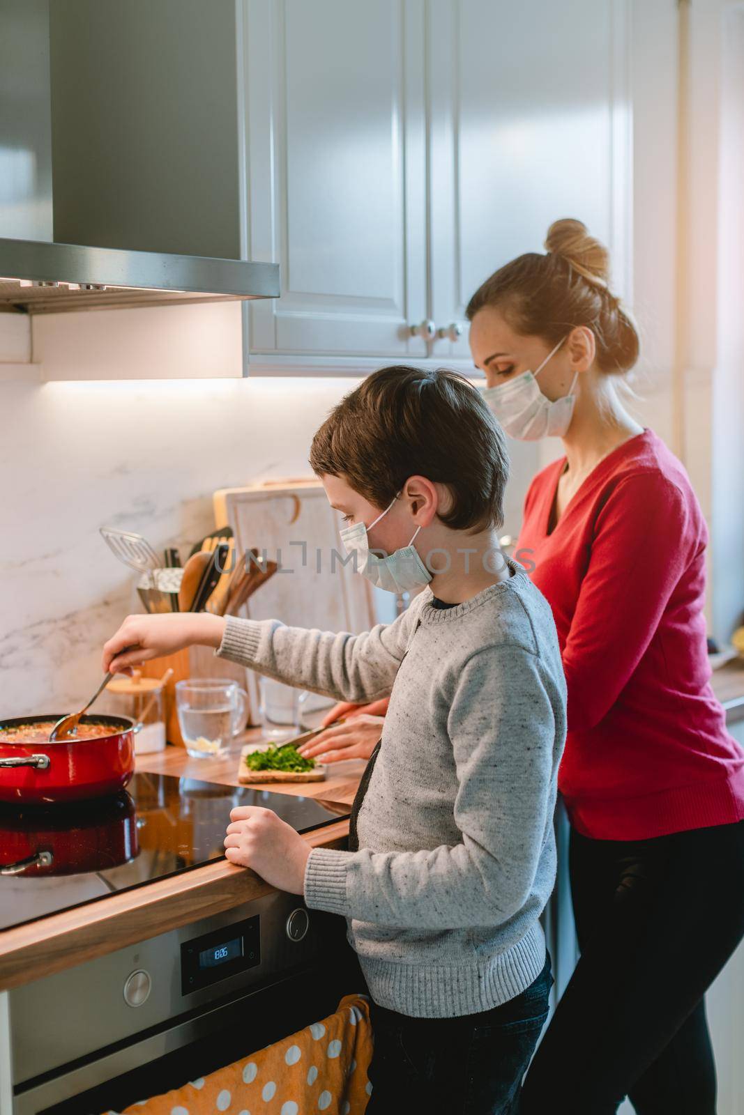 Mother and son cooking at home during the crisis time wearing masks