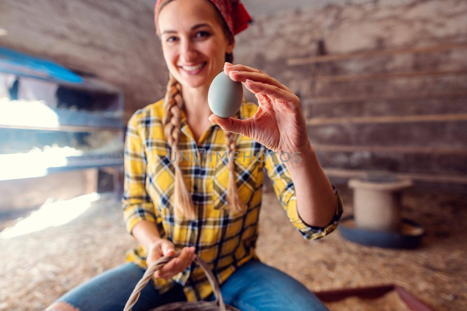 Happy farmer woman showing egg she just collected in a henhouse