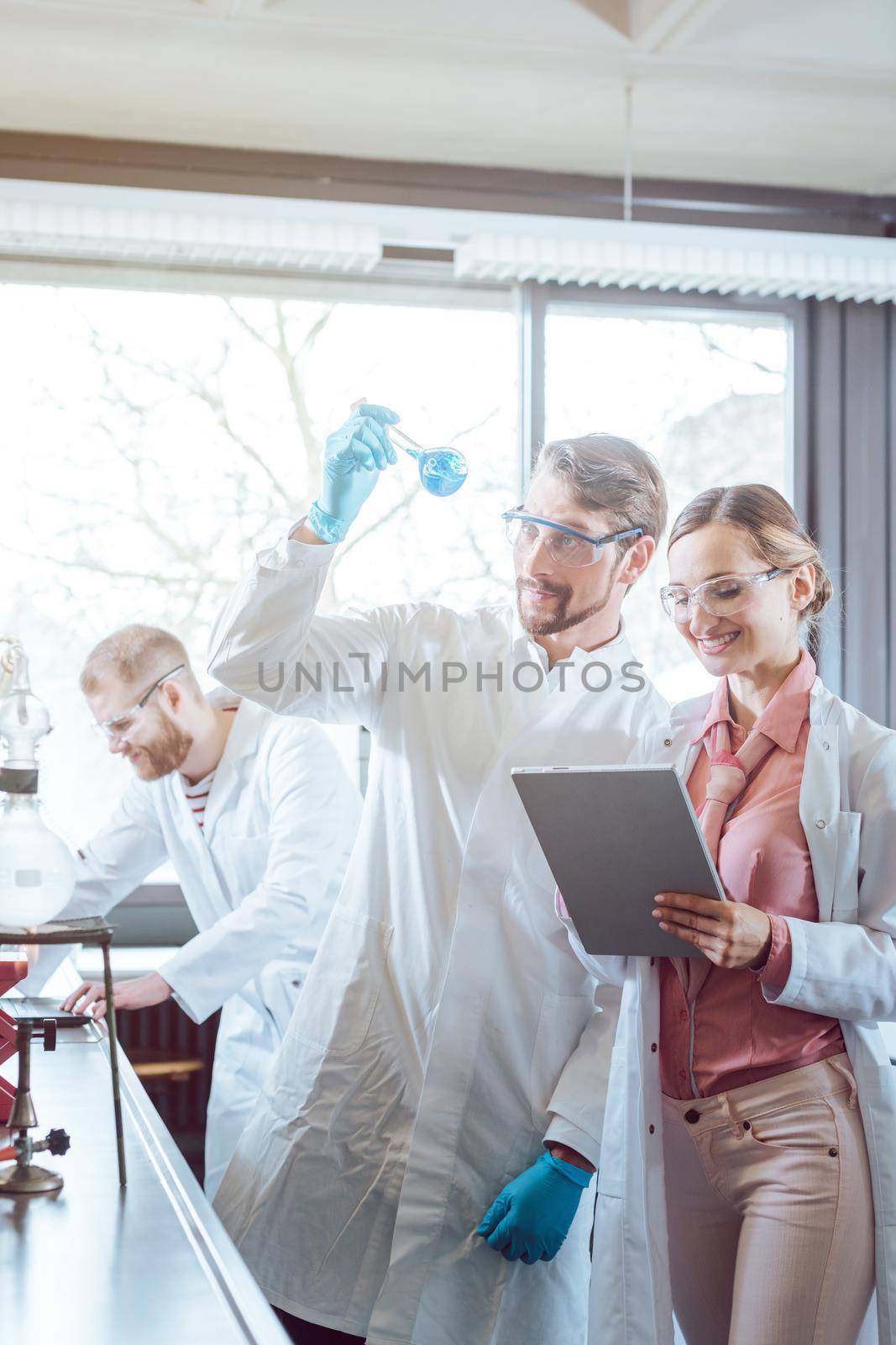 Team of scientists during experiment in the lab looking at test glass