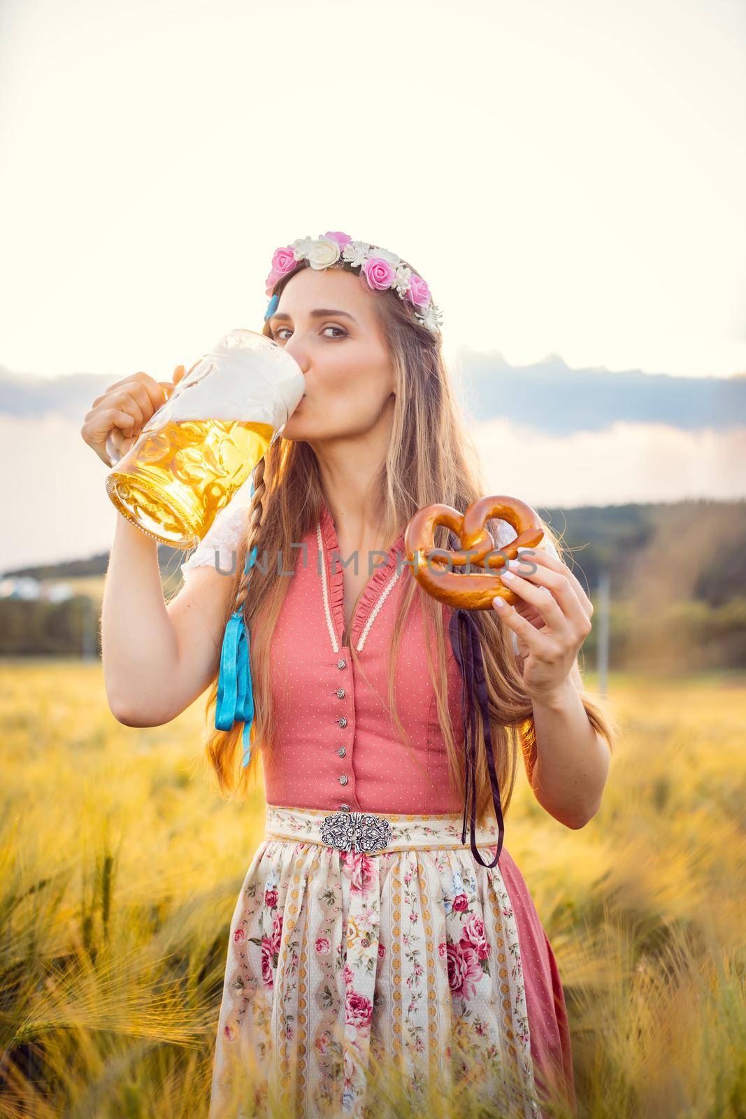Woman in traditional clothing drinking beer in Bavaria by Kzenon
