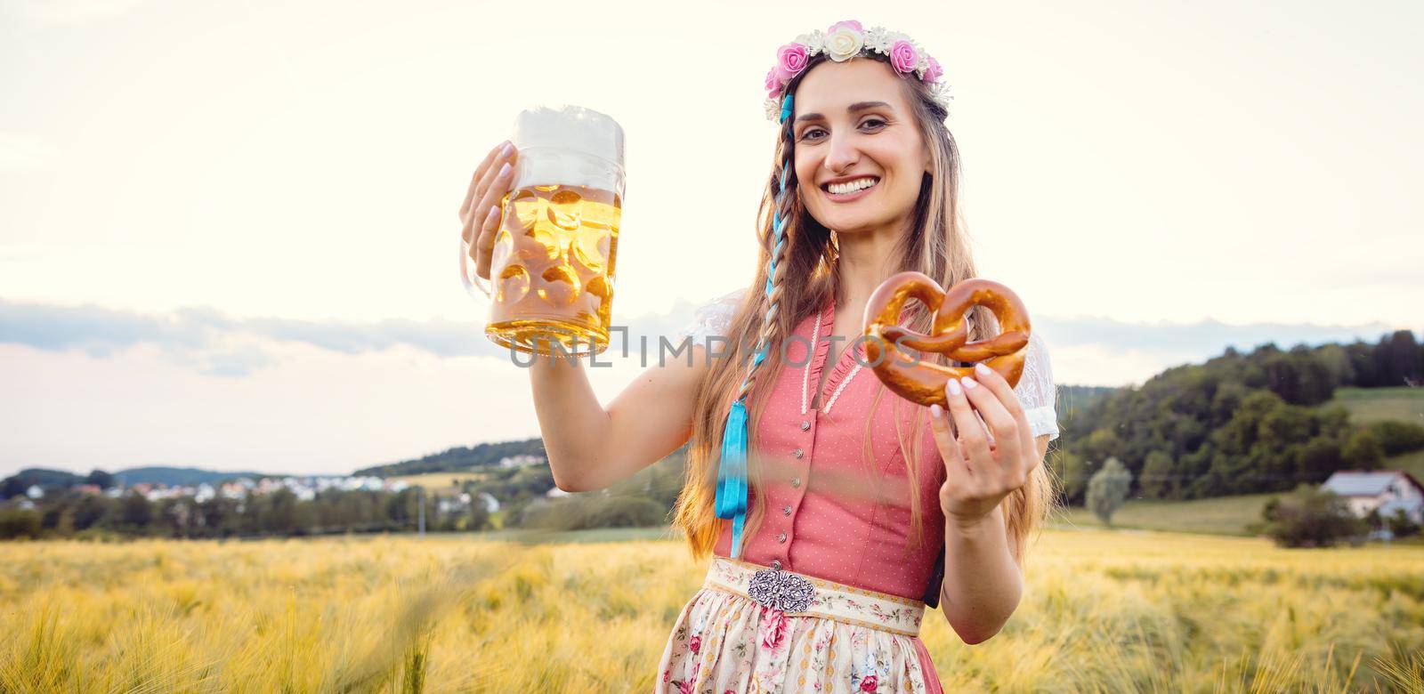 Happy Bavarian woman with beer and traditional food in summer during sunset