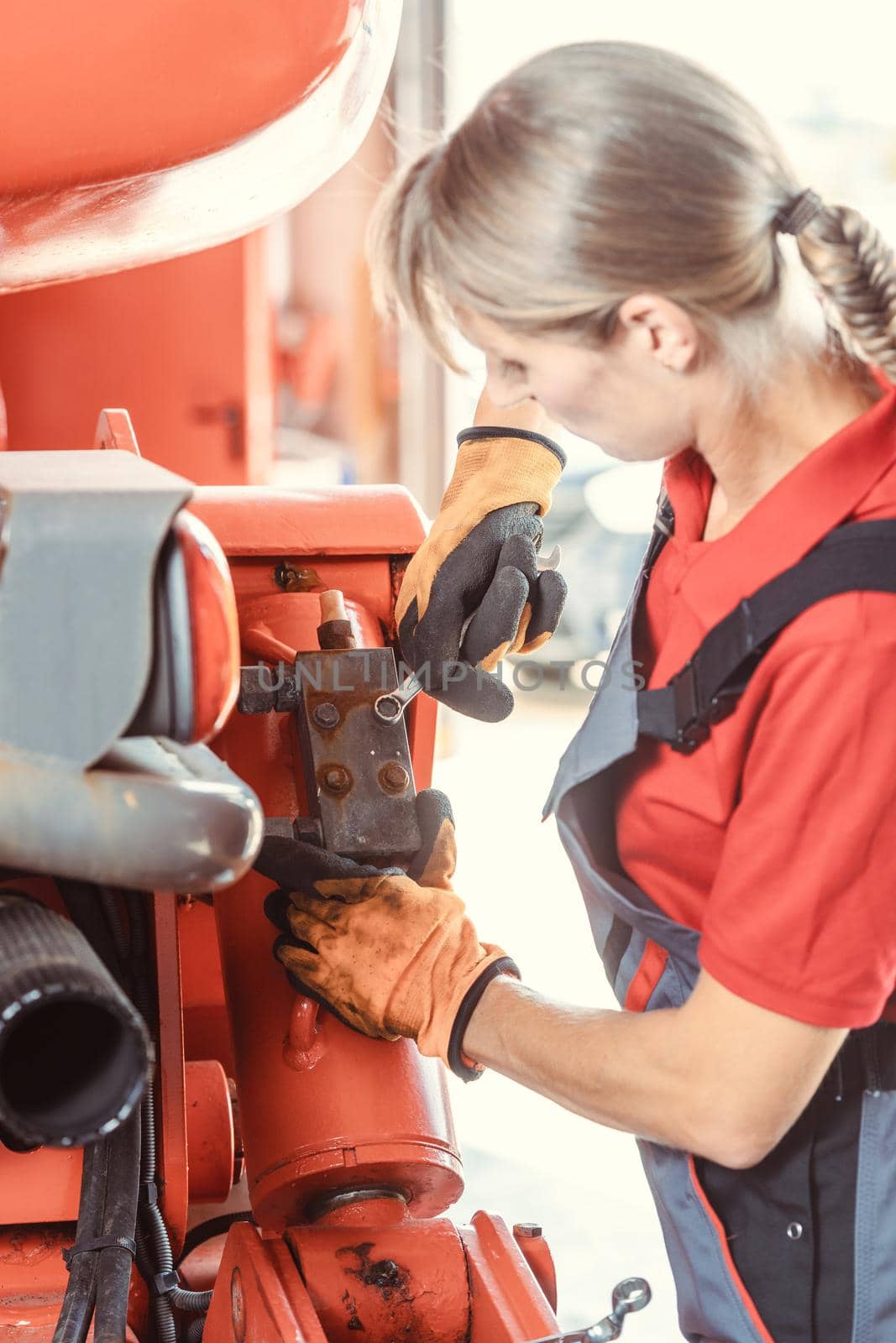 Woman machinist working with wrench of a farm machine by Kzenon