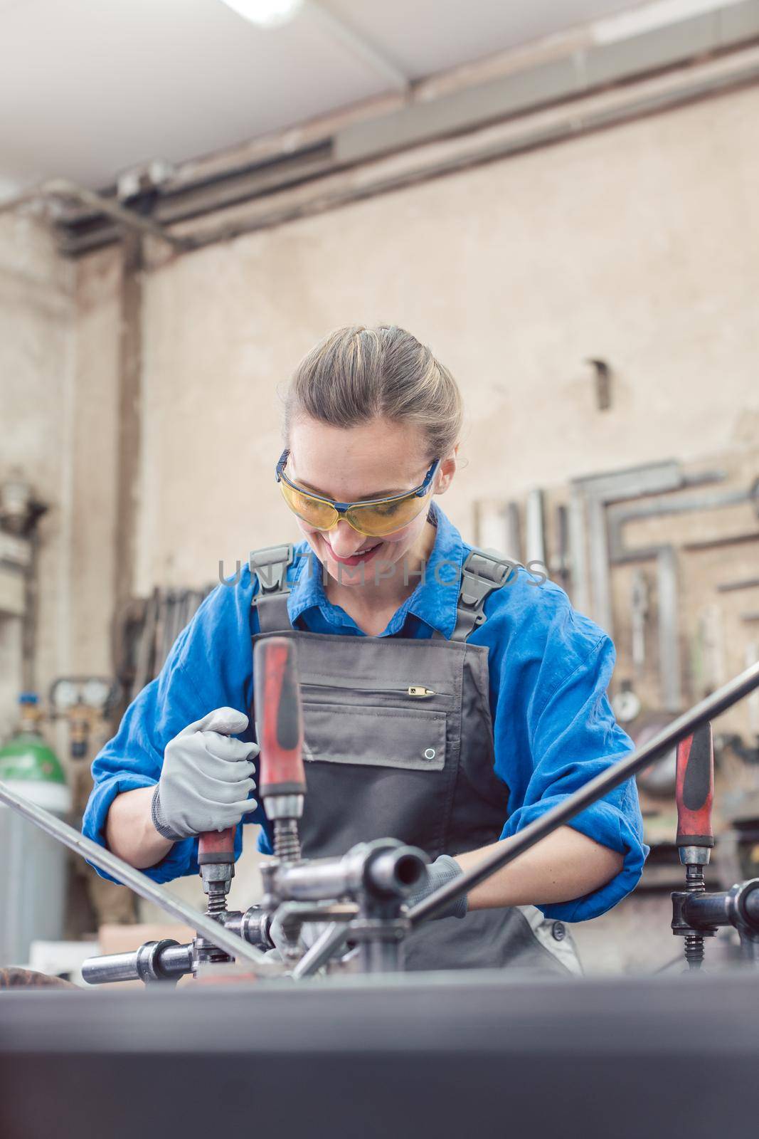 woman in Metal workshop with tools and workpiece working hard