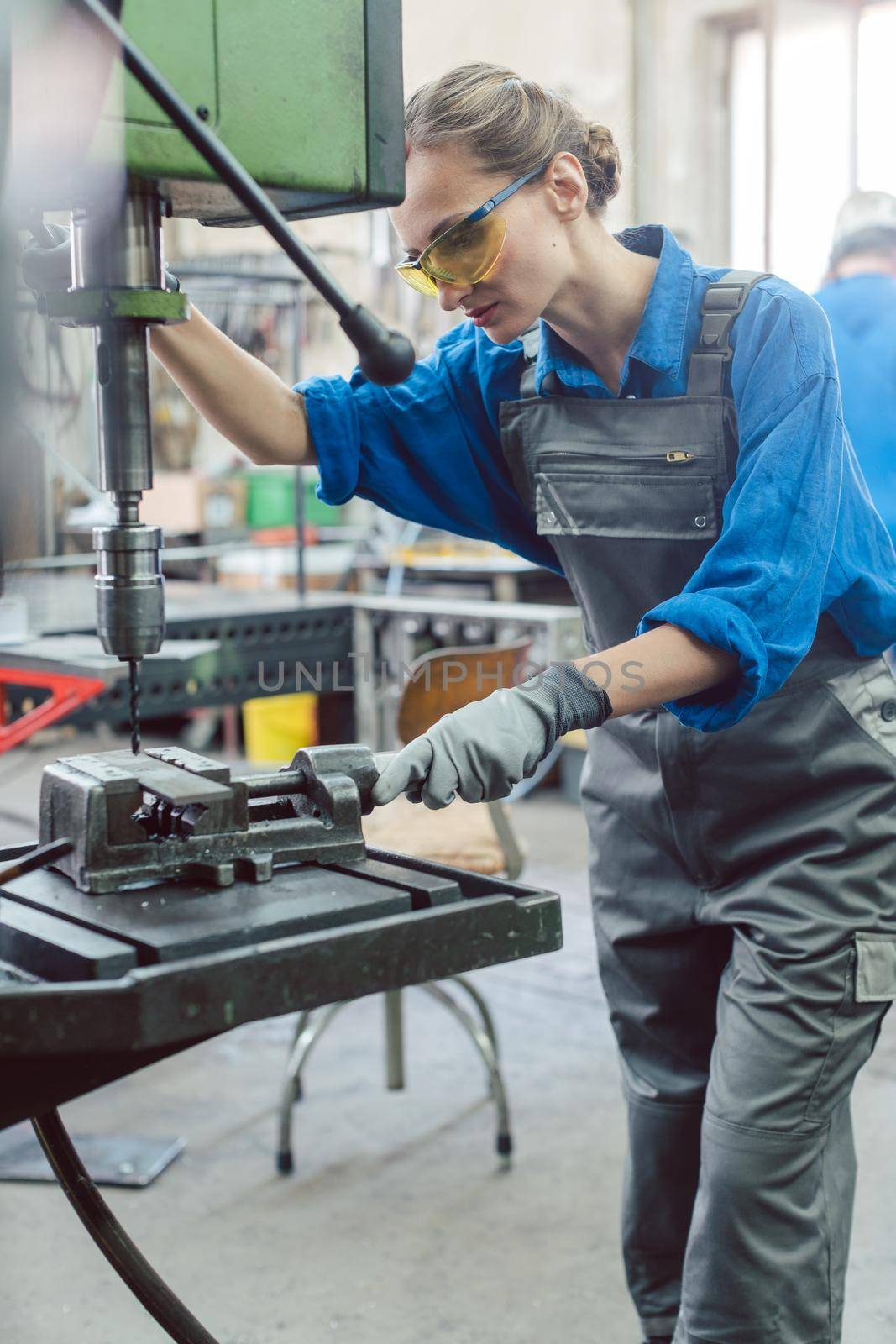 Metal worker woman operating drilling machine concentrating on her job